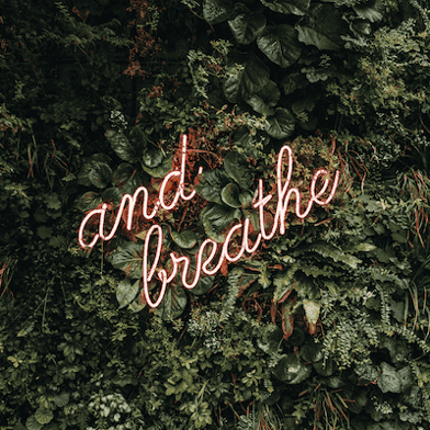 A neon sign that reads "and breathe"
