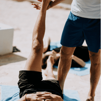 A fitness instructor helping a fitness member stretch their leg